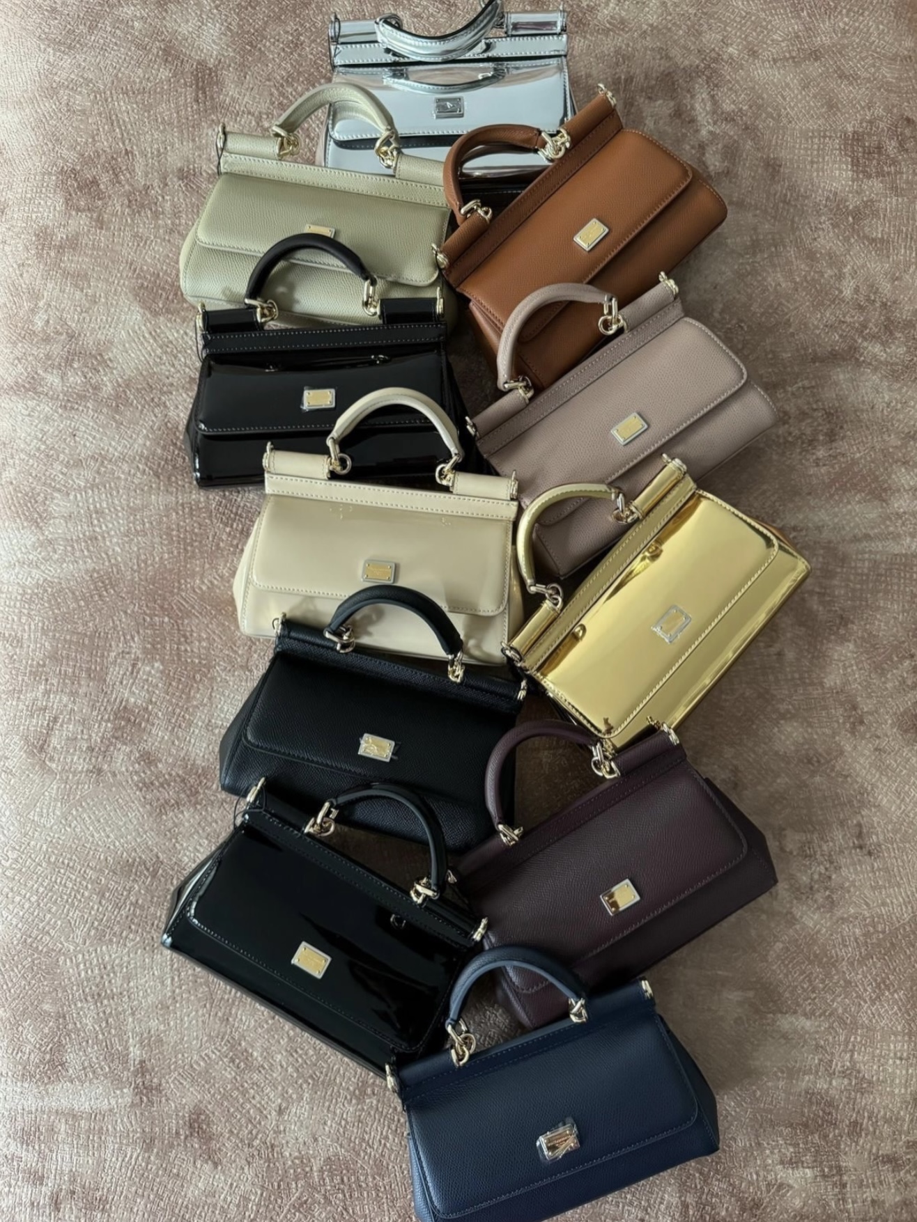 A lineup of Dolce & Gabbana Sicily bags in multiple colors and leather textures.