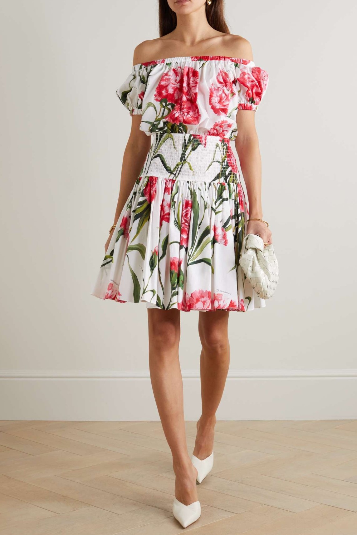 An off-the-shoulder shirred floral-print cotton mini dress styled for a summer resort look.