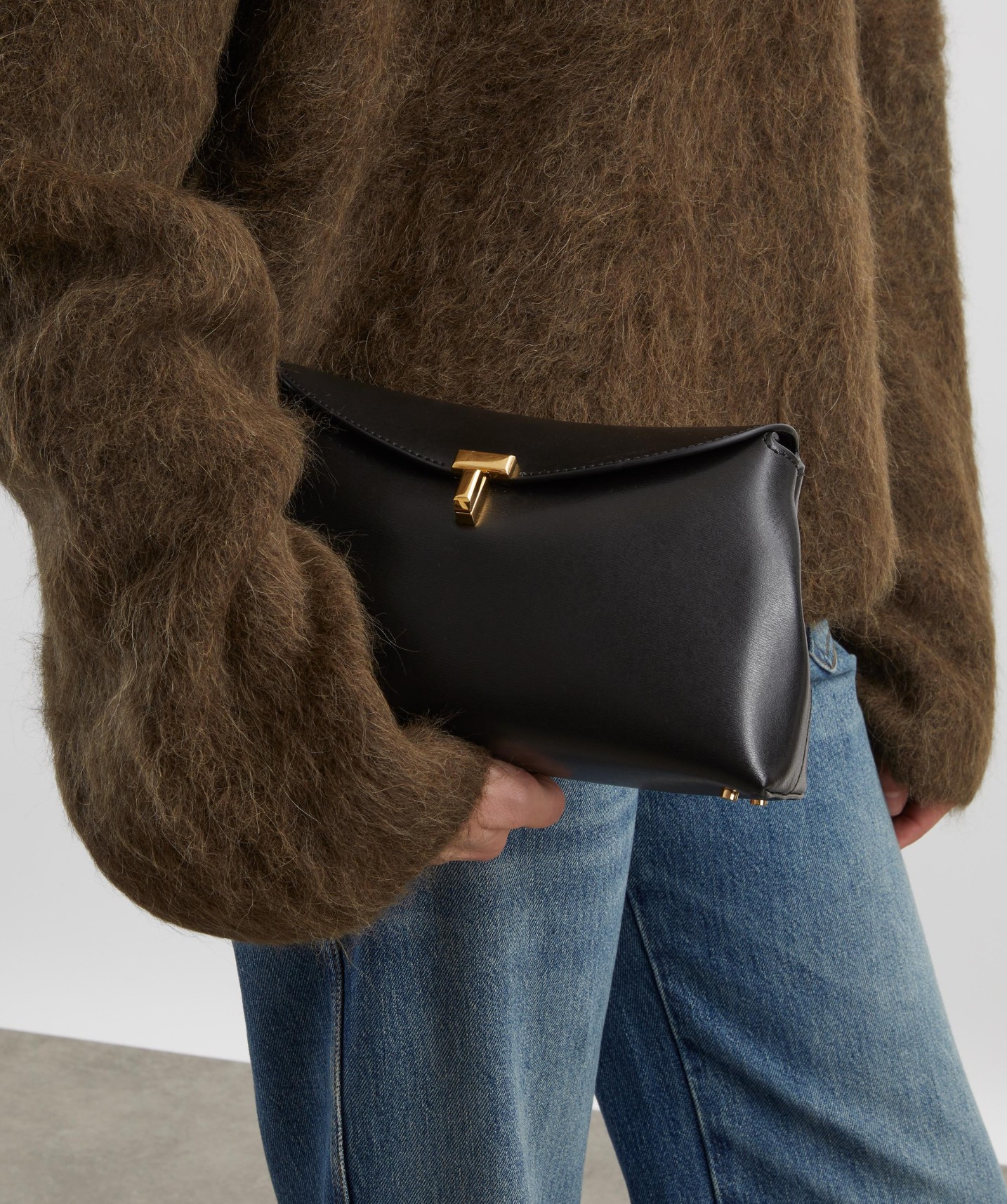 TOTEME T-Lock clutch bag in black grain leather.